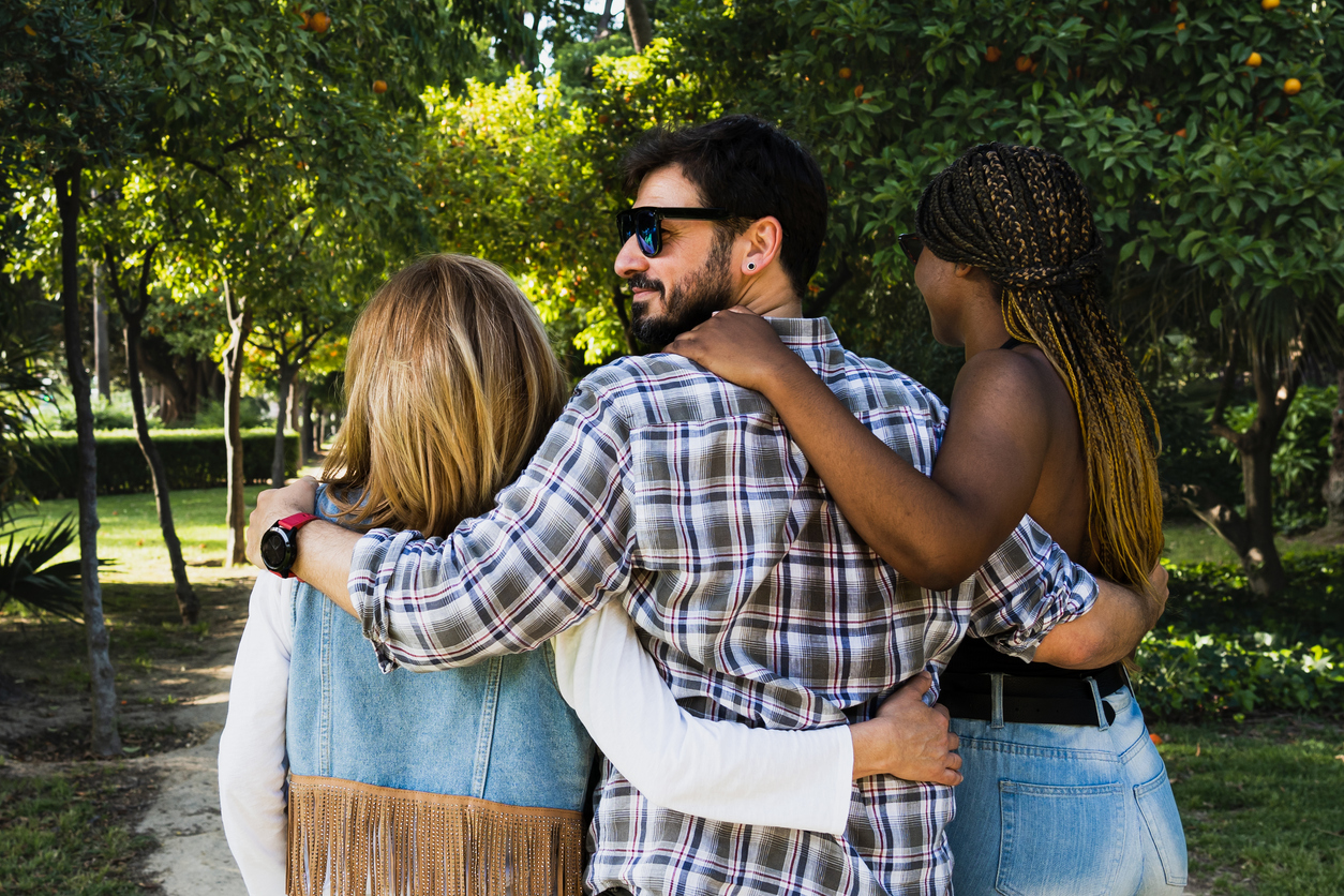 Multiracial group of friends walking in a natural park. Polyamorous relationship concept.